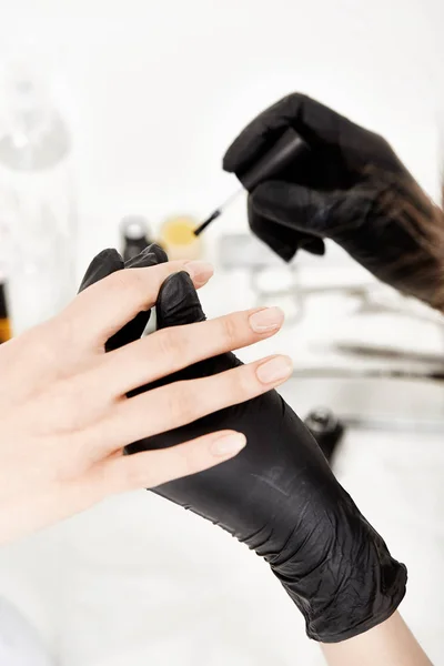 Nail artist in gloves holding woman hand
