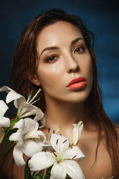 Young amazing woman stading shirtless behind tender flowers. Fashion photography.