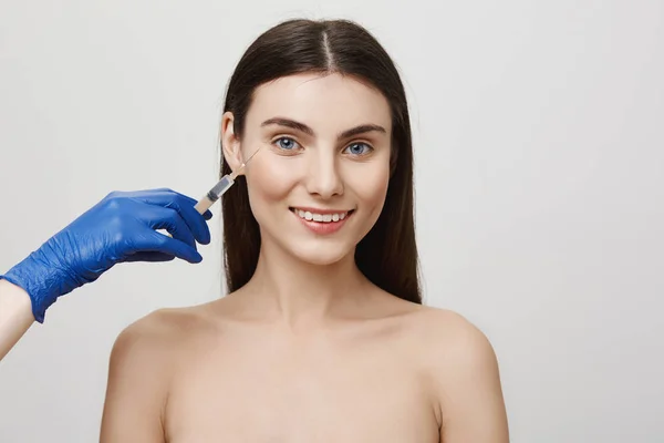 Happy woman can not wait to become perfect. Attractive female standing naked in cosmetological salon, waiting to receive injection to get rid of wrinkles and stop aging, glad to be in talented hands