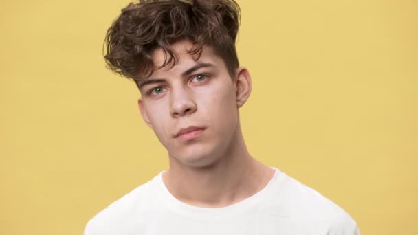 Closeup Portrait Of Teenage Boy With Short Curly Hair And Green Eyes Posing On Camera With Candid Smile Isolated Over Yellow Background