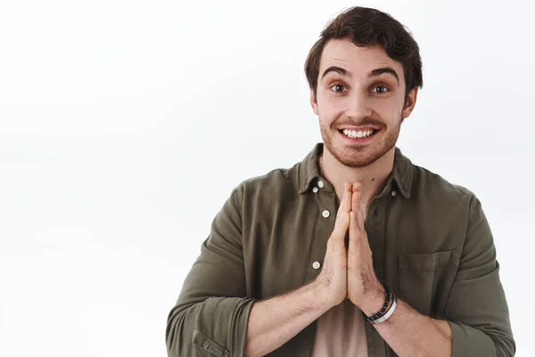 Handsome young cute male student asking classmate cover him, hold palms clasped together and smiling, do me favour, please gesture, want help from you, standing white background pleading pose