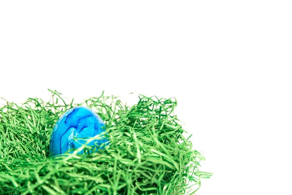 Paas-ei in een nest van Pasen gemaakt van groen gras en witte achtergrond — Stockfoto