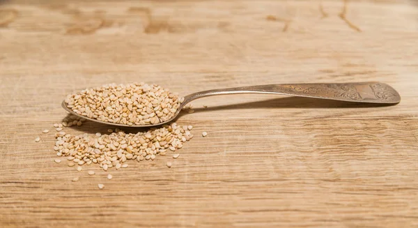 Silver spoon with sesame seeds on a wooden board