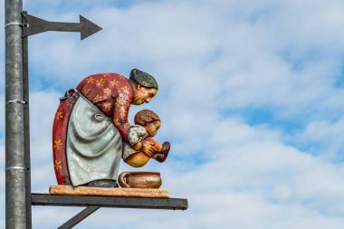Bir çocuk bir çömleği yukarıda tutan yaşlı bir kadın ile tuvalet işareti