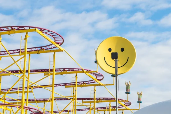 Satellitenschüssel als Smiley mit Joyride im Hintergrund auf einem Volksfest — Stockfoto