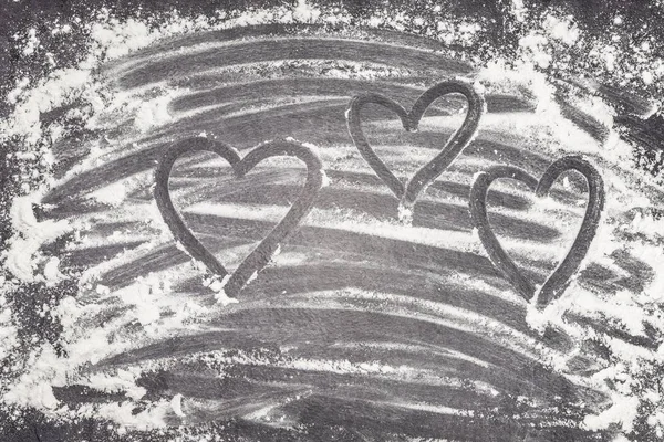 Herzen mit Finger in Weizenmehl auf graue Arbeitsfläche gemalt — Stockfoto