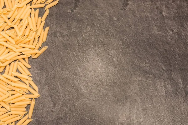 Penne Rigate pasta de macarrones sobre una superficie de trabajo gris —  Fotos de Stock