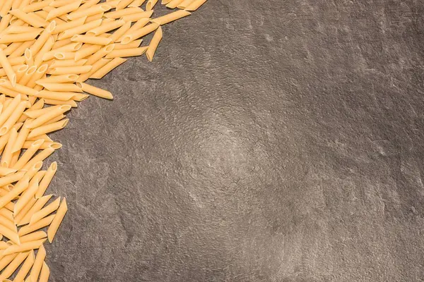 Penne Rigate pasta de macarrones sobre una superficie de trabajo gris —  Fotos de Stock