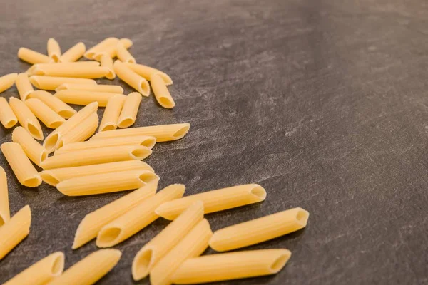 Penne Rigate pasta de macarrones sobre una superficie de trabajo gris —  Fotos de Stock