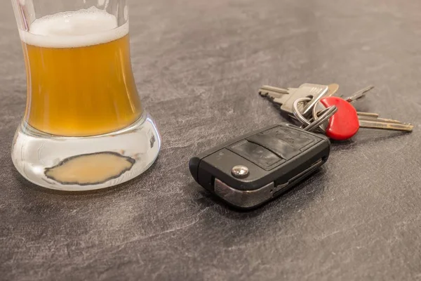 Glass of Beer and car key on grey table — Stock Photo, Image