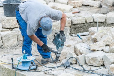 İnşaat işçisi bir taş plaka ile elektrik kesintisi kesiyor