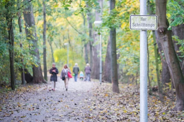 Kinderwagen in een park in het najaar met Duitse straat teken alleen wandelen tempo — Stockfoto