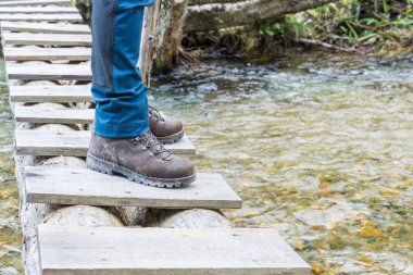 Bir dere yürüyüş botları ağaç gövdesi üzerinde köprü