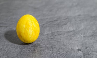 Gri arka plan önünde sarı Paskalya yortusu yumurta