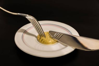 Altın sikke bitcoin bıçak ve siyah arka plan üzerine izole çatal ile plaka üzerinde