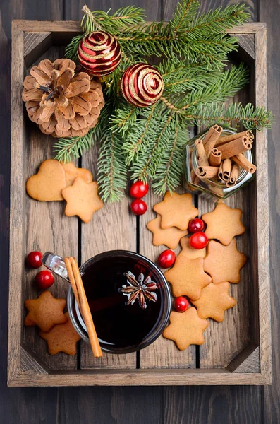 Рождественское глинтвейна. Концепция праздника украшена еловыми ветвями, пряничным печеньем и клюквой на темном деревянном подносе . — стоковое фото
