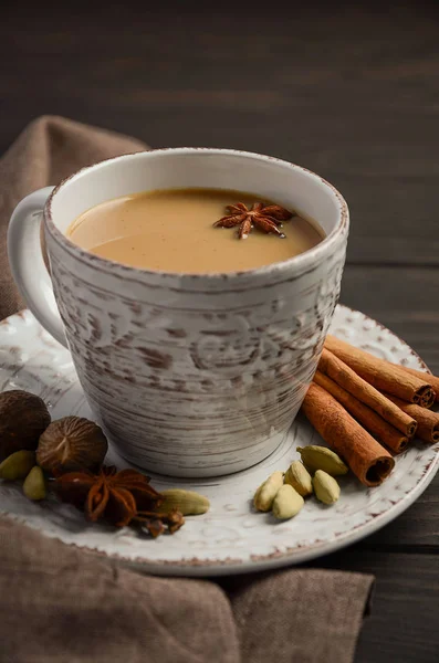 Indická masala chai čaj. Kořeněný čaj s mlékem na rustikální dřevěný stůl. — Stock fotografie