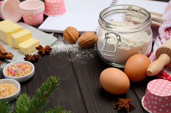 Рождественская выпечка ингредиенты кексы формы, специи, масло, яйца и мука на темном деревянном фоне — стоковое фото