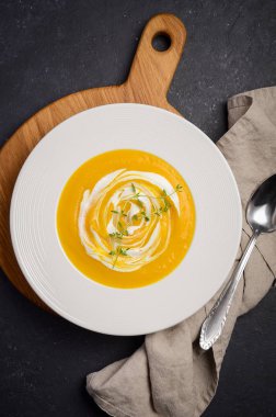 Krem ve siyah arka plan üzerine kekik ile kabak krem çorbası