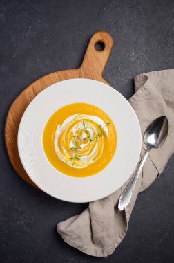 Krem ve siyah arka plan üzerine kekik ile kabak krem çorbası