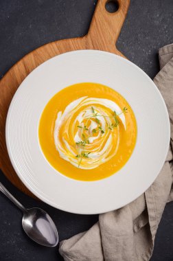 Krem ve siyah arka plan üzerine kekik ile kabak krem çorbası