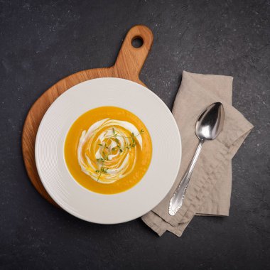 Krem ve siyah arka plan üzerine kekik ile kabak krem çorbası