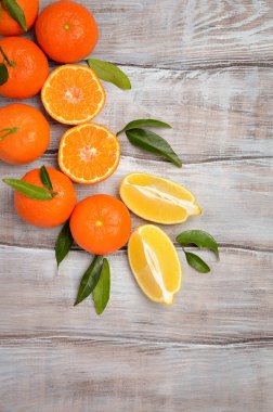Taze mandalina clementine ve limon ile ahşap arka plan yapraklarda