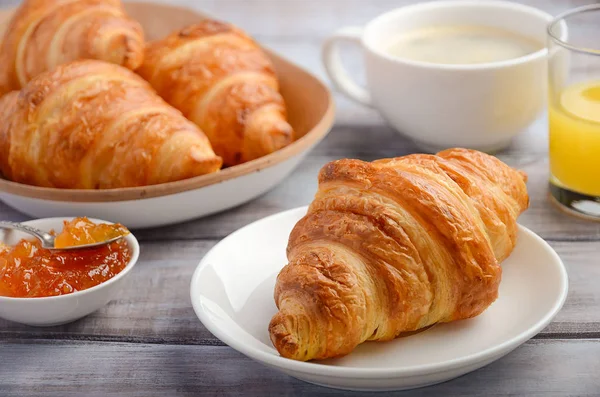 Fresh Croissants with coffee, jam and orange juice for breakfast on rustic wooden background. — Stock Photo, Image