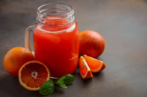 Jugo de naranja de sangre fresca en tarro de albañil sobre fondo oscuro —  Fotos de Stock