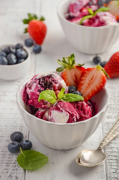 Helado con arándanos y fresas en tazón blanco sobre fondo de madera blanca — Foto de Stock