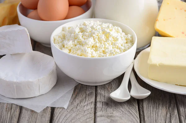 Färska mjölkprodukter. Mjölk, ost, brie, Camembert, smör, yoghurt, keso och ägg på träbord. — Stockfoto