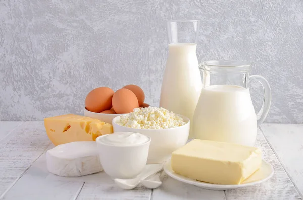 Productos lácteos frescos. Leche, queso, brie, Camembert, mantequilla, yogur, requesón y huevos sobre mesa de madera . — Foto de Stock