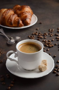 Koyu arka plan üzerinde kruvasan ile taze kahve