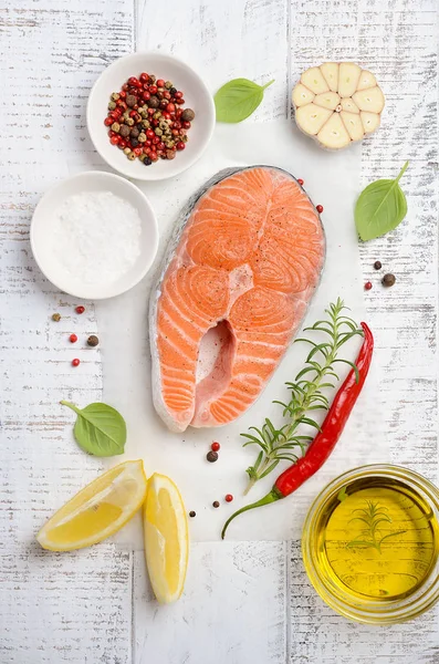 Filete fresco de salmón crudo con limón, aceite de oliva y especias sobre fondo rústico de madera. Ingredientes para hacer una cena saludable. Concepto de dieta saludable . — Foto de Stock