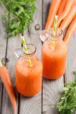 Taze havuç suyu şişelerde rustik ahşap zemin üzerine