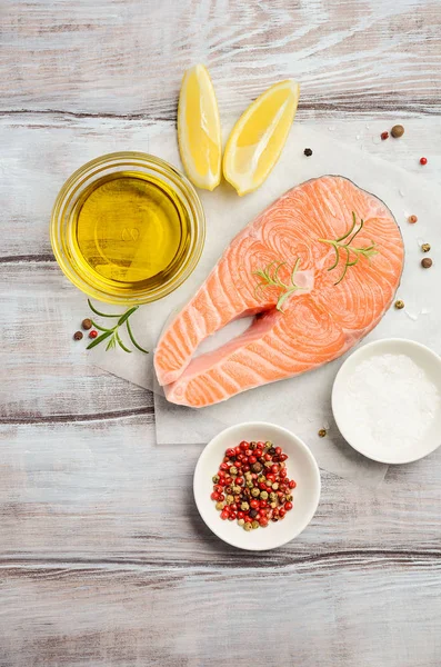 Bistecca di salmone crudo fresco con limone, olio d'oliva e spezie su fondo rustico in legno. Ingredienti per preparare una cena sana. Dieta sana concetto . — Foto Stock