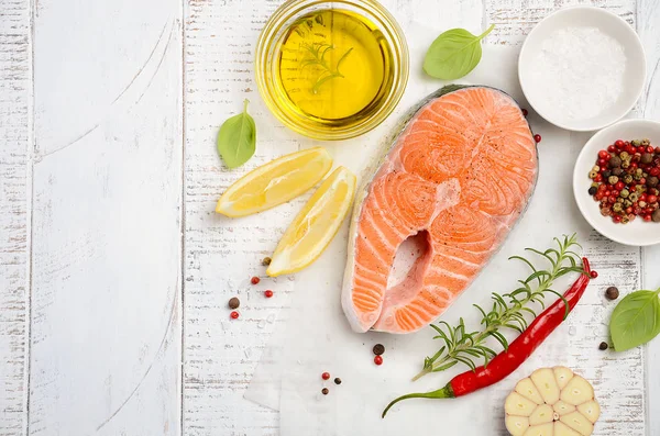 Färsk rå lax biff med citron, olivolja och kryddor på rustika trä bakgrund. Ingredienser för att göra hälsosam middag. Hälsosam kost koncept. — Stockfoto