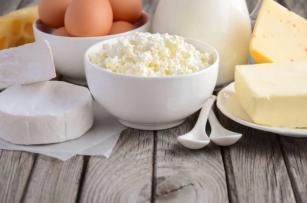 Produtos lácteos frescos. Leite, queijo, brie, Camembert, manteiga, iogurte, queijo cottage e ovos em mesa de madeira . — Fotografia de Stock