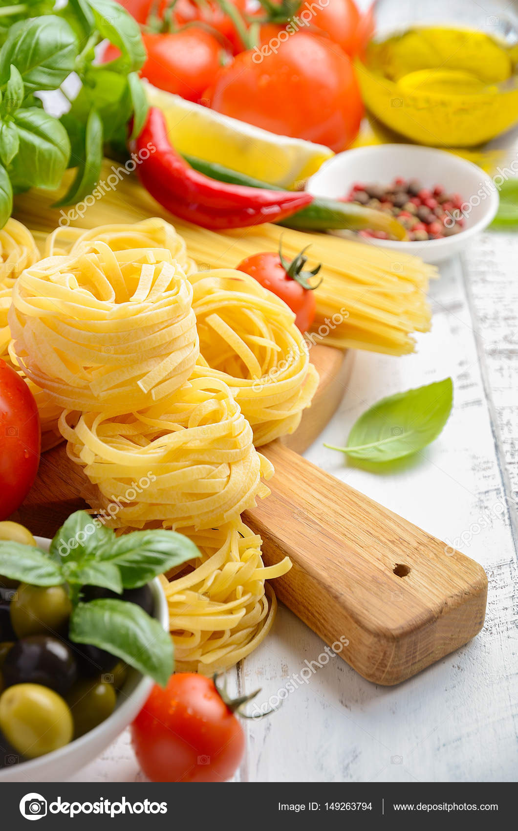 Pasta, vegetables, herbs and spices for Italian food on white wooden