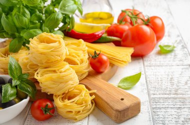 Makarna, sebzeler, otlar ve baharatlar Beyaz ahşap zemin üzerinde İtalyan gıda için