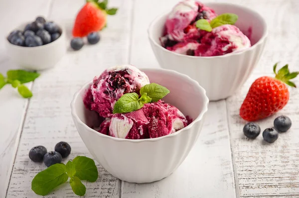 Helado con arándanos y fresas en tazón blanco sobre fondo de madera blanca — Foto de Stock