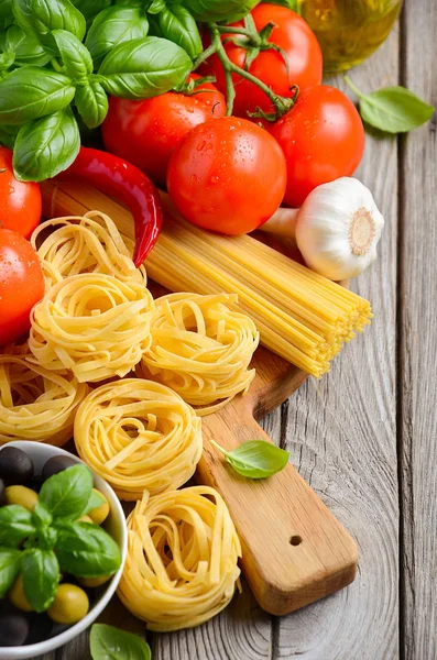Pasta, Gemüse, Kräuter und Gewürze für italienische Speisen auf Holzgrund — Stockfoto
