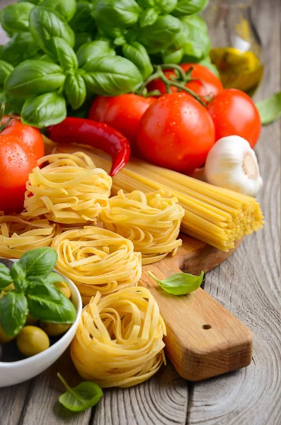 Pasta, vegetables, herbs and spices for Italian food on wooden background — Stock Photo, Image