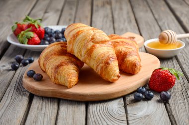 Taze kruvasanlar rustik ahşap zemin üzerine taze çilek ile