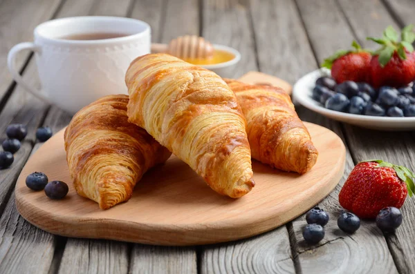 Fresh Croissants with fresh berries on rustic wooden background — Stock Photo, Image