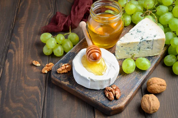 Mängd ost med druvor, valnötter och honung. — Stockfoto