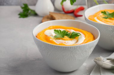 Krem ve maydanoz bir gri beton veya taş arka plan ile kabak çorbası