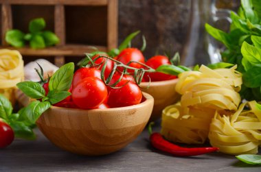 Pişmemiş makarna, fesleğen, biber ve sarımsak İtalyan yemeği için taze kırmızı kiraz domates.