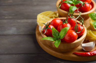 Pişmemiş makarna, fesleğen, biber ve sarımsak İtalyan yemeği için taze kırmızı kiraz domates.