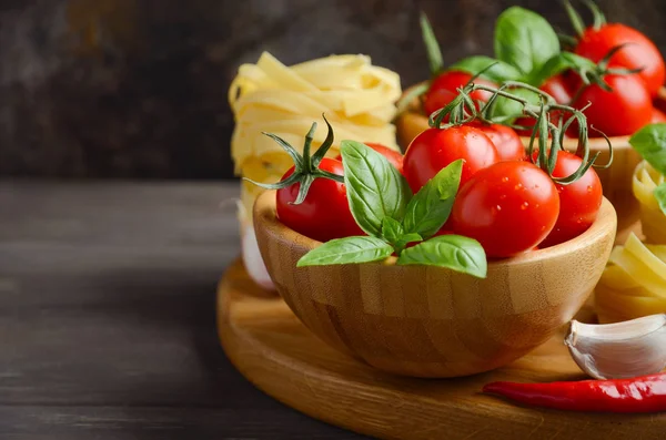 Pişmemiş makarna, fesleğen, biber ve sarımsak İtalyan yemeği için taze kırmızı kiraz domates.